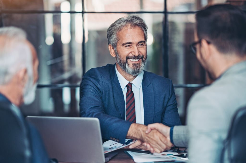 Mature businessman shake hands with a younger colleague
